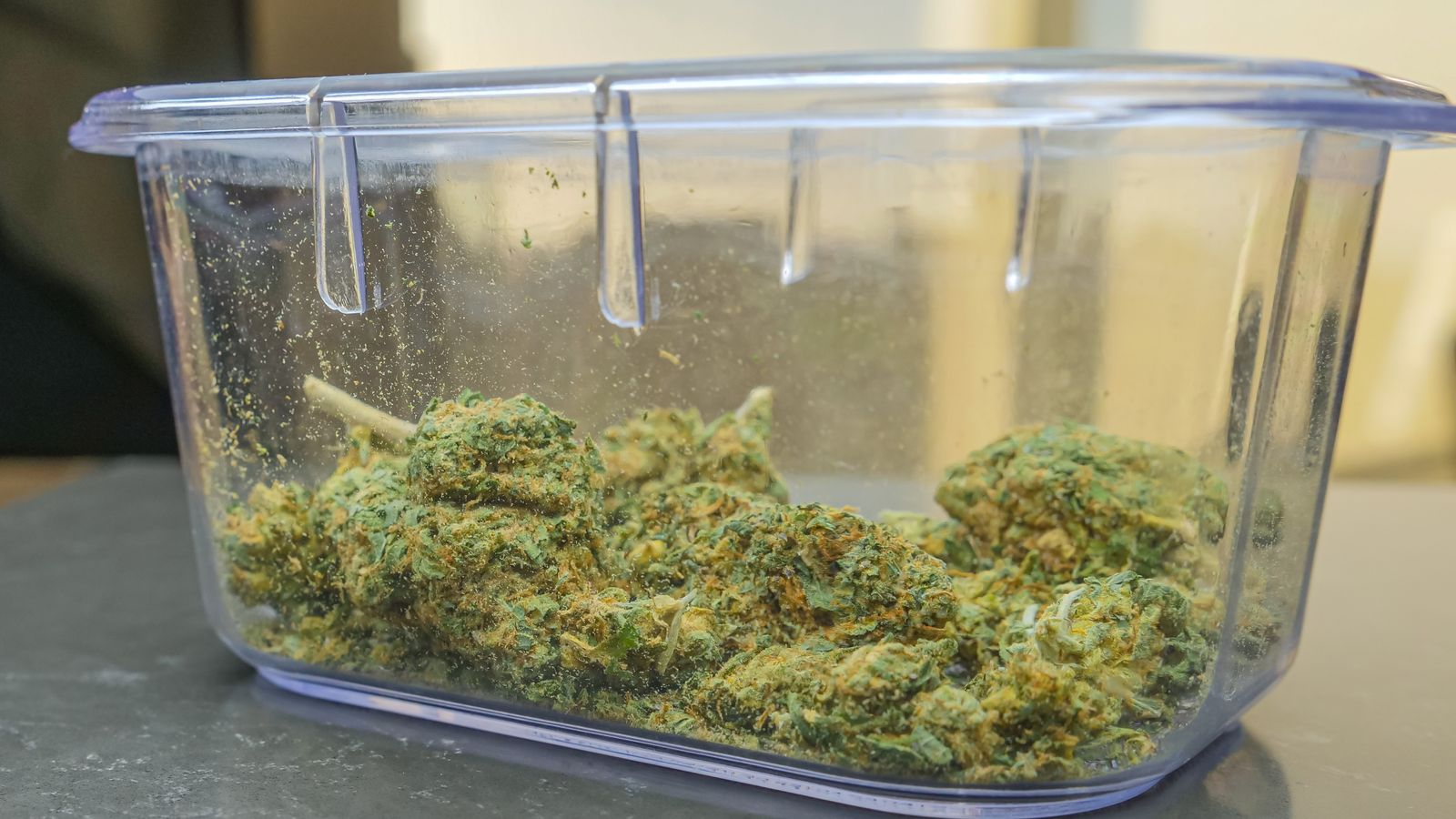 A close-up shot of cannabis buds stored in a clear glass container, highlighting the texture and color.