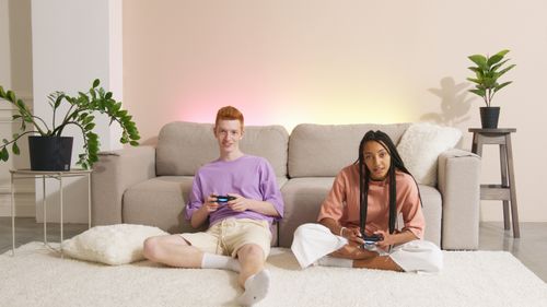 Free Two friends playing video games together in a cozy living room setting. Stock Photo