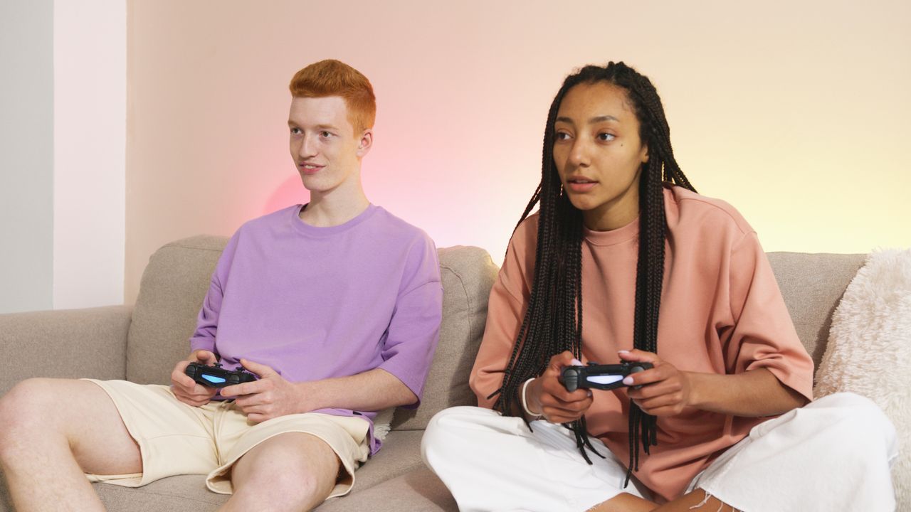 two young adults enjoying video gaming on a comfortable sofa at home