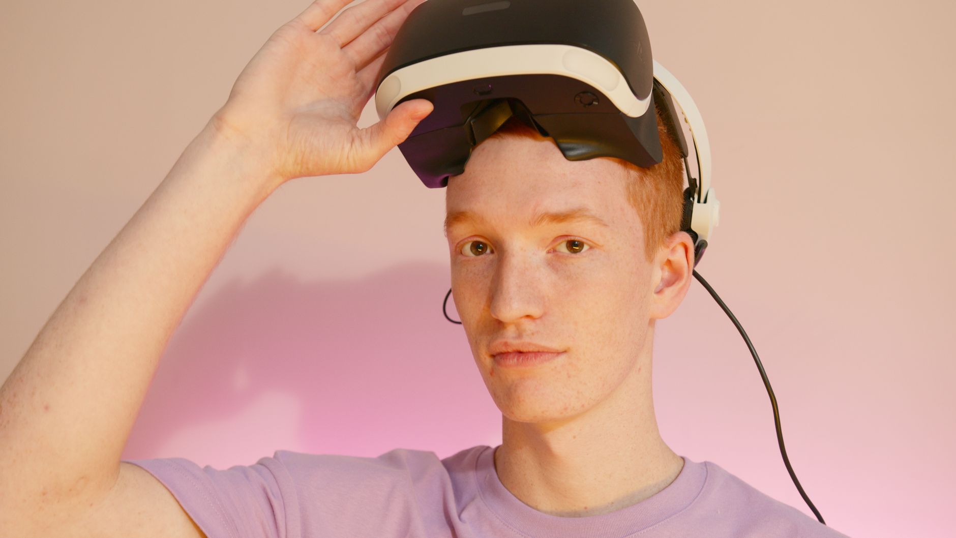 Caucasian man wearing and adjusting a VR headset in a minimalist indoor setting.