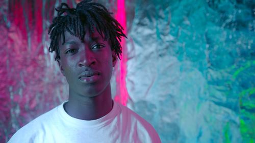 Free Close-up portrait of a young man with dreadlocks in vibrant lighting. Stock Photo