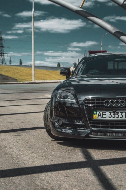 Free A shiny black Audi luxury car parked outdoors under structural shadows. Stock Photo