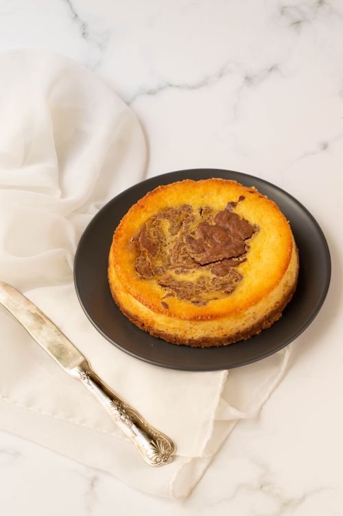 Free Delicious chocolate swirl cheesecake on a black plate with vintage knife, perfect dessert indulgence. Stock Photo