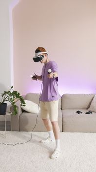 A young man wearing a VR headset and holding controllers enjoys a game in a modern living room.