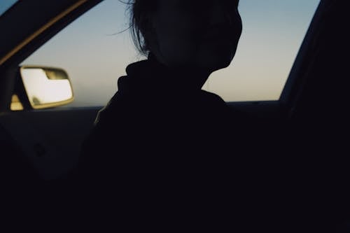 Anonymous woman in dark car in evening