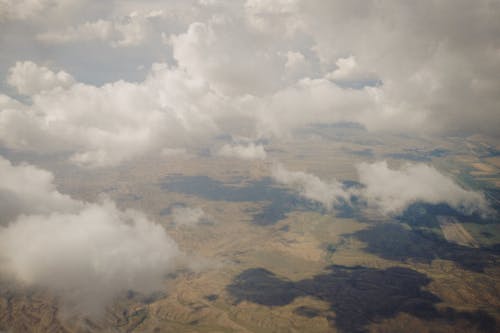 Breathtaking view of white fluffy clouds above beige endless hills located in mountainous valley in daytime