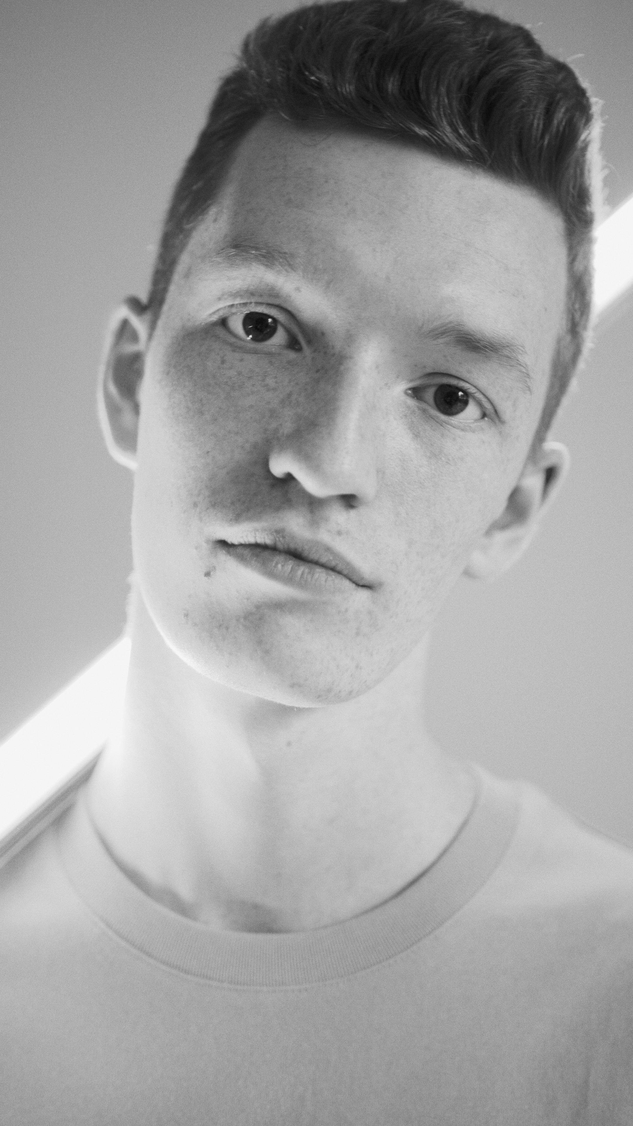 Striking black and white portrait of a young man with soft lighting.