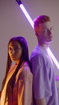 Artistic portrait of a man and woman against vibrant neon lighting, creating a modern and dramatic atmosphere.