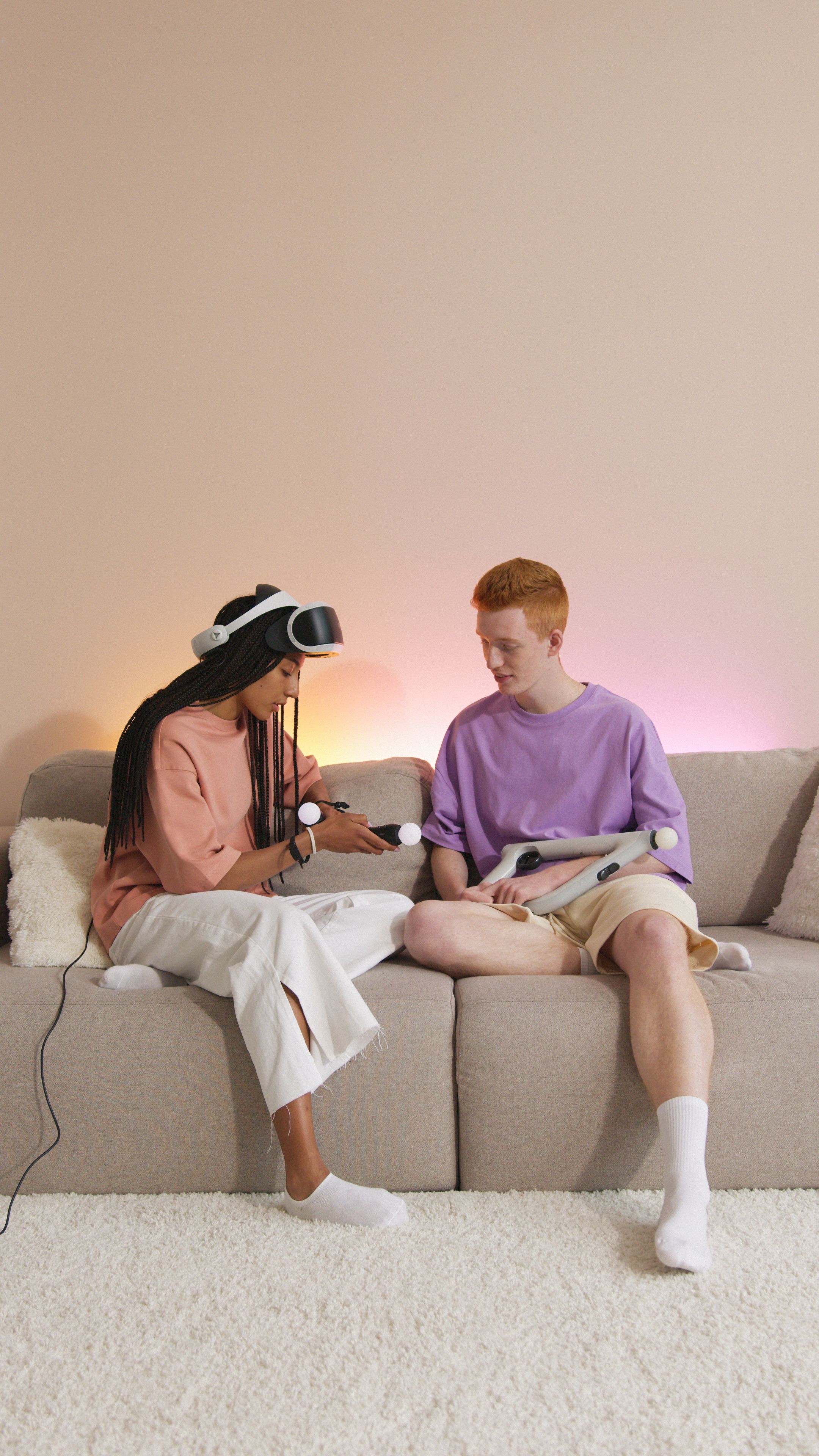 Free Young couple sitting on a sofa, immersed in a virtual reality gaming session. Stock Photo