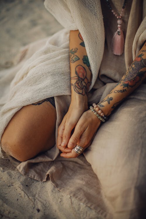 Crop woman with tattoos on sand