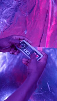 Close-up of hands holding a retro game controller in neon lighting setting.