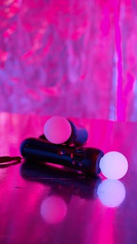 Close-up of illuminated gaming motion controllers on a pink reflective background, ideal for tech and gaming themes.