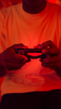 Hands holding a game controller, bathed in orange light, creating a vibrant gaming atmosphere.