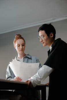 Two diverse professionals reviewing documents together at a table indoors.