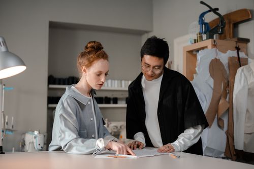 Free Two designers collaborate in a stylish fashion studio, focusing on their creative work. Stock Photo