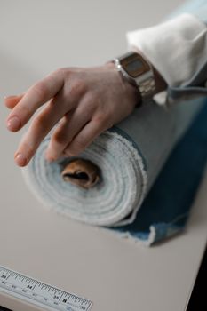 A hand wearing a stylish wristwatch rests on a rolled fabric, showcasing fashion and design elements.