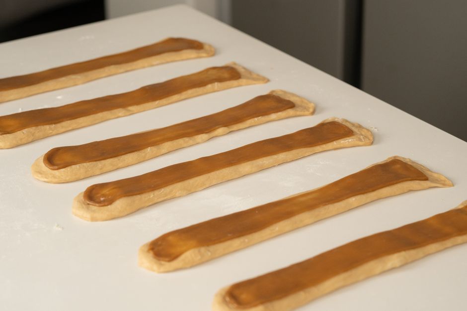 Close-up of homemade pastry dough strips on a kitchen table ready for baking.