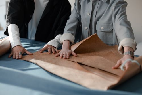 Free Two designers collaborating on paper patterns for tailoring projects. Stock Photo