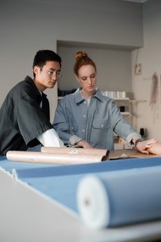 Two fashion designers working on dressmaking in a modern studio.