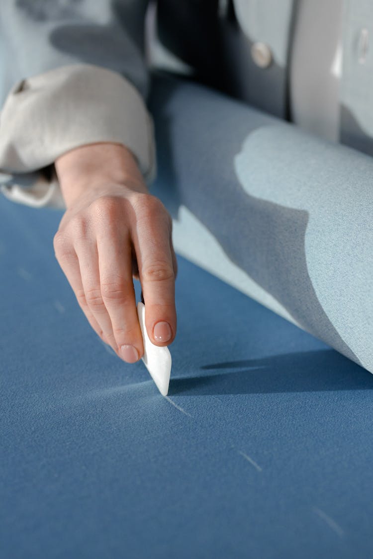 Person Putting A Mark On Blue Textile With A Tailor's Chalk