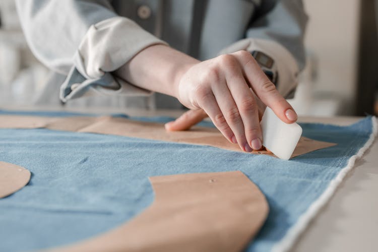 A Person Marking A Fabric Using A Tailor's Chalk