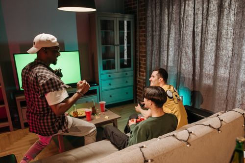 Free Three friends playing video games together in a cozy home setting. Stock Photo