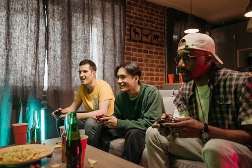 Free Three diverse friends playing video games together at home, enjoying leisure time. Stock Photo