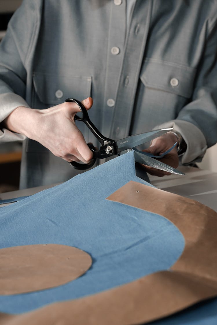 Person Cutting A Blue Fabric