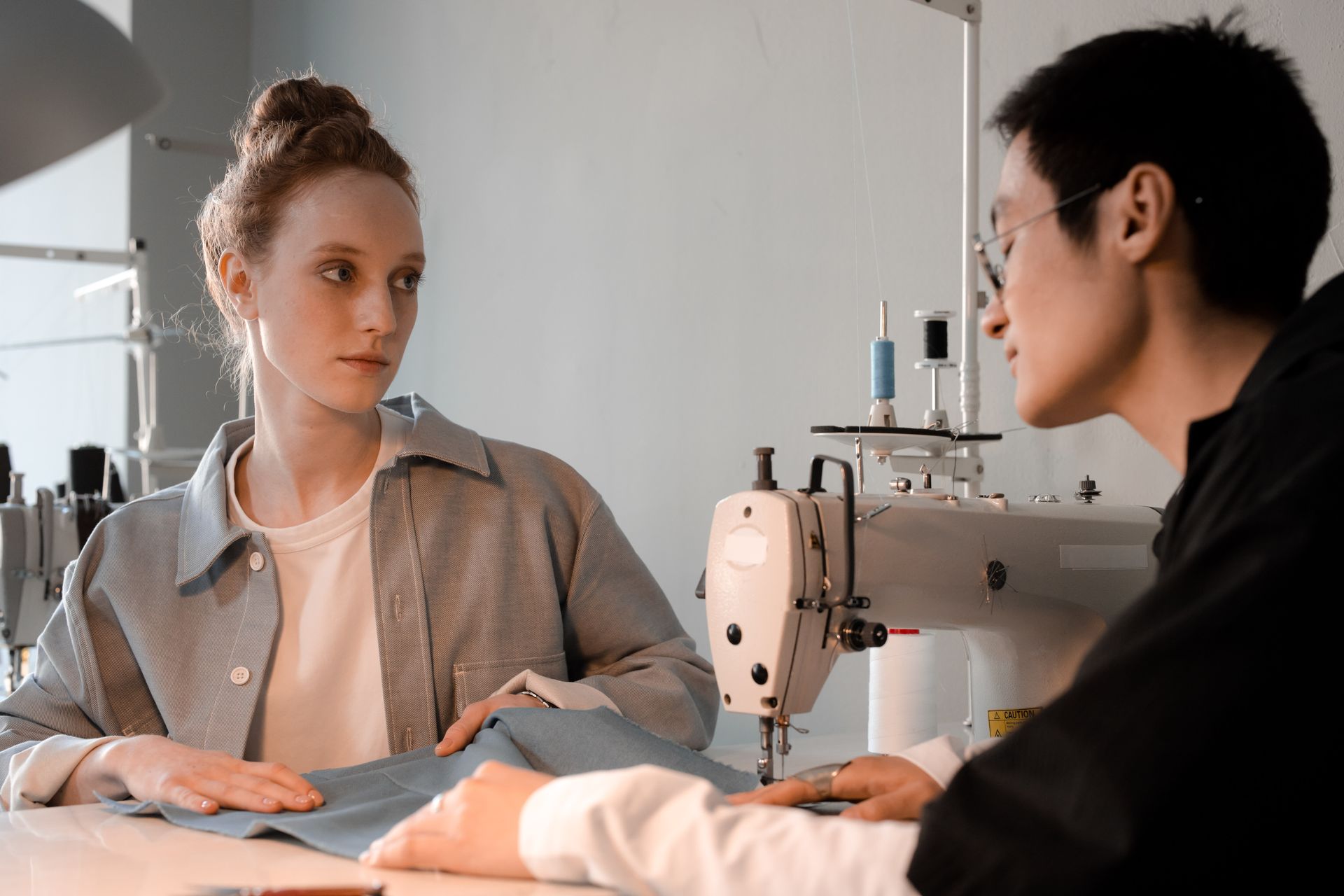 Fashion designers collaborating in a workshop with sewing machines and fabrics.