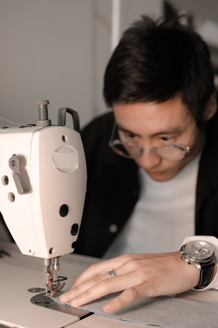 A Man Sewing A Fabric On A Sewing Machine