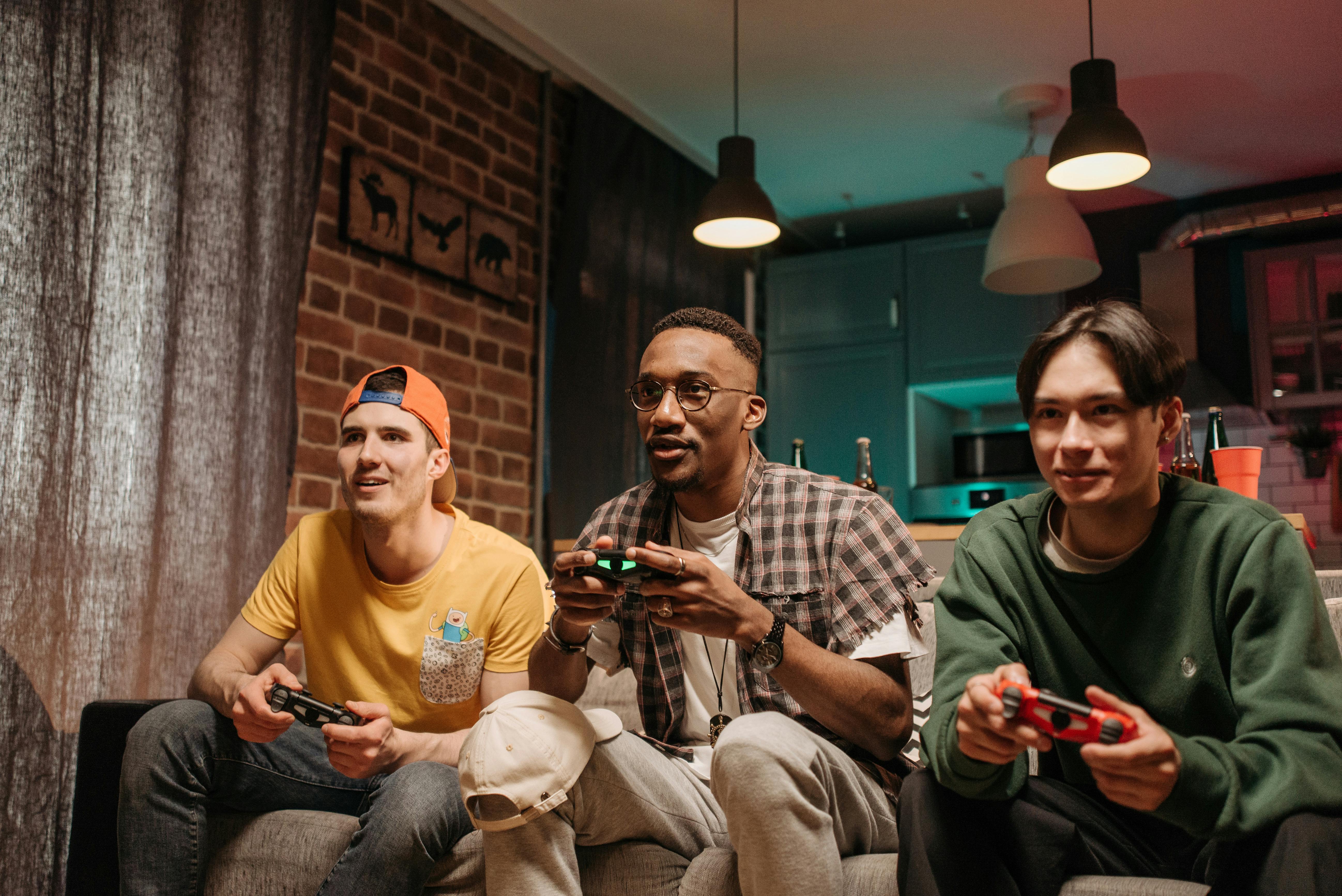 men sitting on sofa holding game controllers