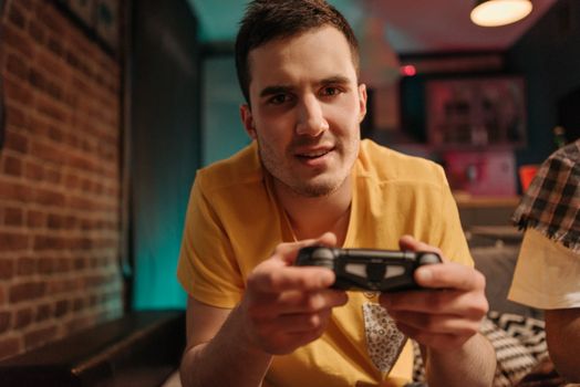 Focused young man enjoying video games with a controller indoors.