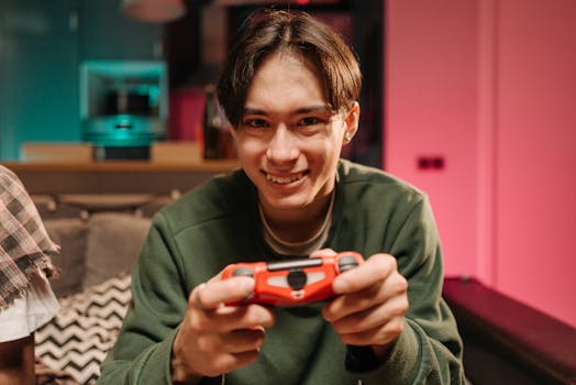 A cheerful young man playing video games with a game controller in a colorful indoor setting.