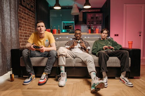 Gamers Sitting Together on a Brown Sofa