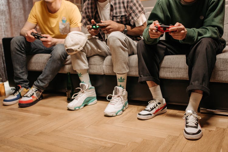 A Group Of People Sitting On A Sofa While Playing Video Games