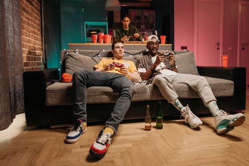 Free A group of diverse young men playing video games together on a sofa, having fun and relaxing indoors. Stock Photo