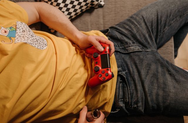 A person relaxing on a couch holding a red game controller