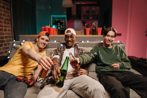 Free Three friends enjoying a night of gaming and drinks, creating lasting memories indoors. Stock Photo