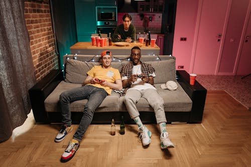 Men Sitting on Gray Couch Playing Computer Games