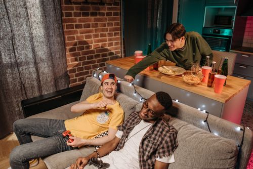 Free Group of friends relaxing and playing video games at home, enjoying leisure time together. Stock Photo