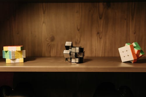 Three Rubik's Cubes On Wooden Shelf