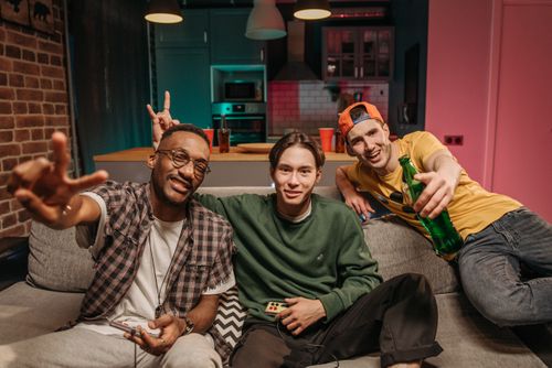 Free Three diverse friends bond over a video game session at home, showcasing fun and friendship. Stock Photo