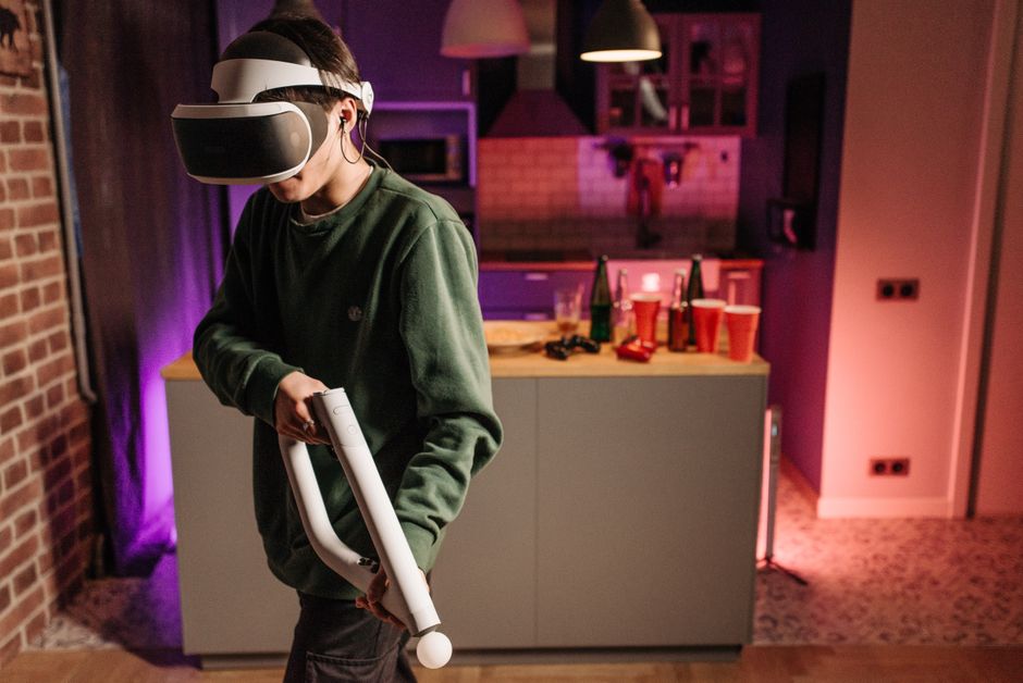 Teen playing VR game in a cozy living room with vibrant lighting.