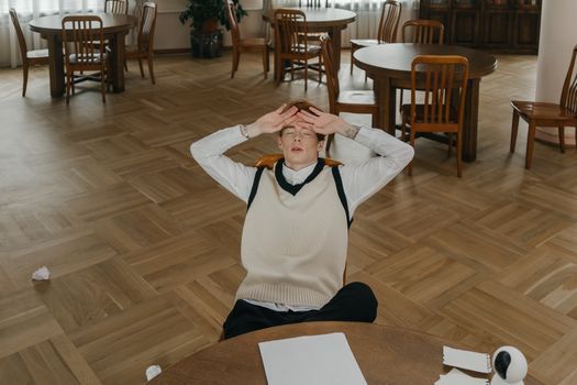 Young man feeling stressed and overwhelmed while studying in a library setting.