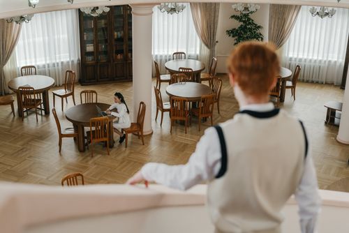 Free An elegant library interior with a woman studying at a round table, viewed from above. Stock Photo