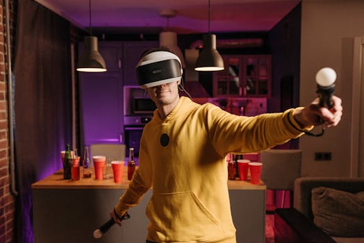 A man in a yellow hoodie immersed in virtual reality gaming at home, using a VR headset and controllers.