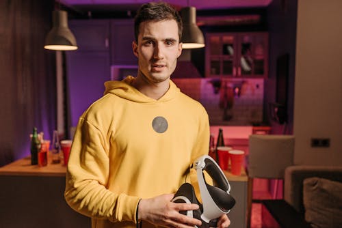 A Man in Yellow Long Sleeves Holding VR Headset