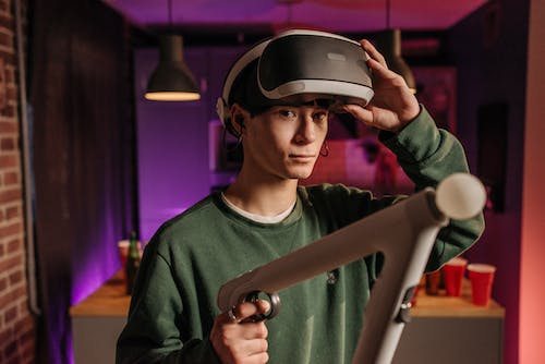 A Man in Green Long Sleeves Playing with VR Controller