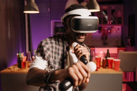 Man wearing VR headset playing video game with controllers in a lively indoor setting.