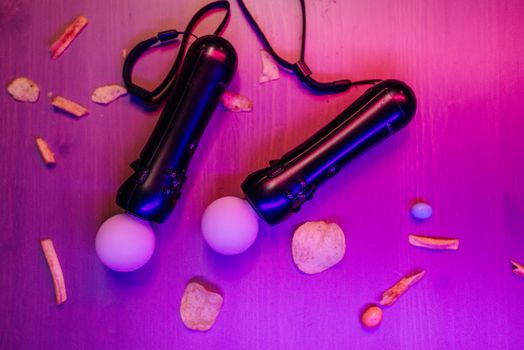 Top view of VR controllers and snacks on a table with vibrant neon lighting.